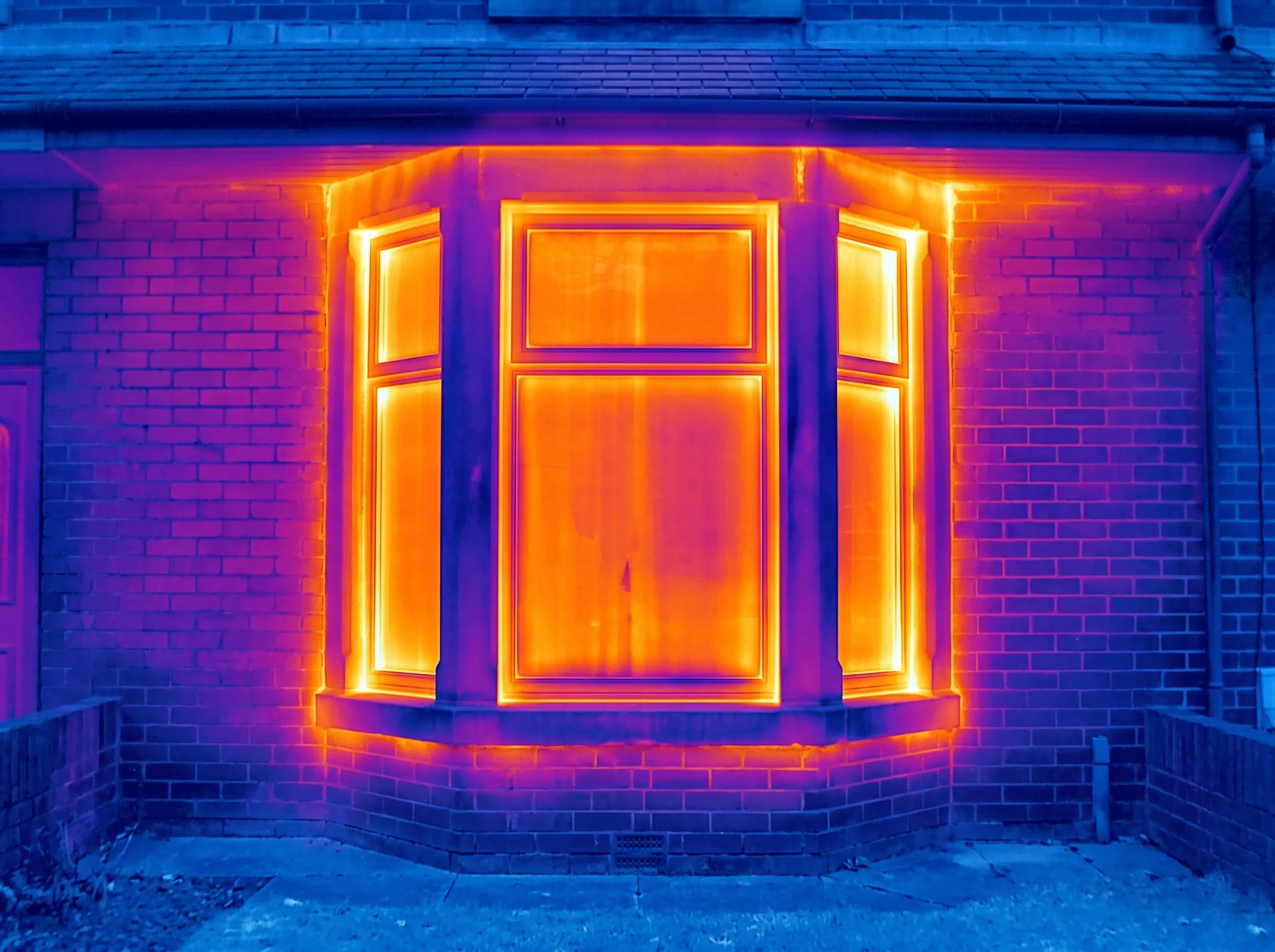 Thermal image of a terrace bay window glowing amber with heat loss before insulation